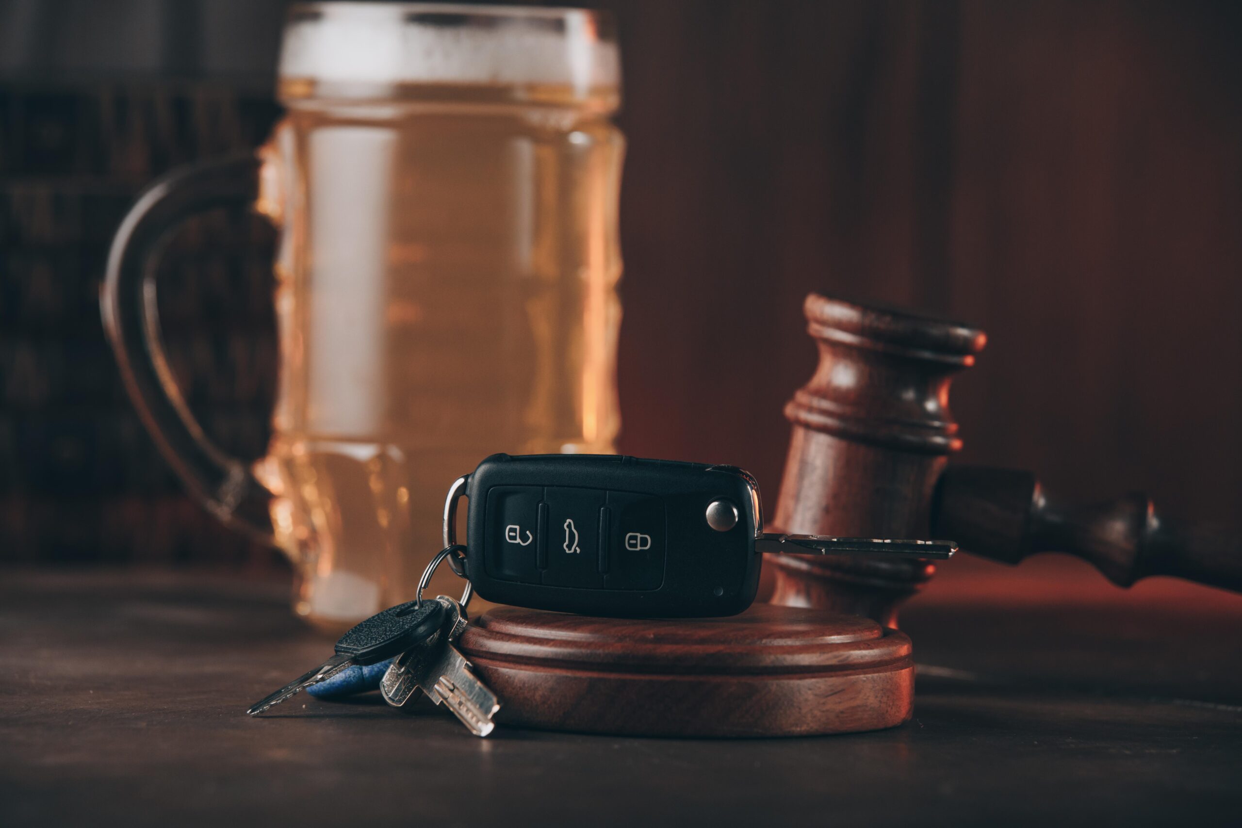 Glass of beer, car keys and judge gavel on a wooden table