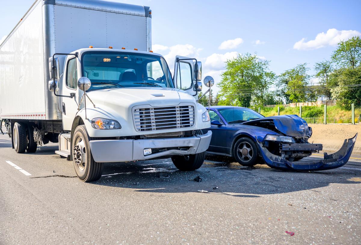 Collision of a semi truck with box trailer a passenger car on the highway road.