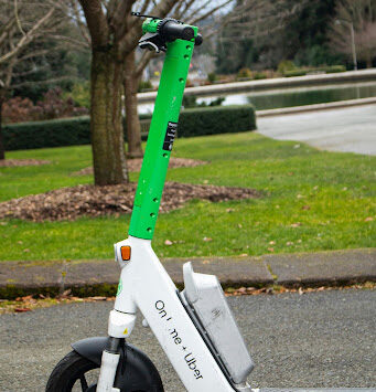 A Lime electric scooter with Lime + Uber branding parked on a paved city path — the type of shared rental scooter used in programs like Everett's, and the kind of micromobility device increasingly involved in Washington personal injury claims.